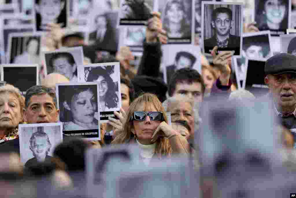 People hold photos of bombing victims as sirens blare during a ceremony marking the 30th anniversary of the bombing of the AMIA Jewish center that killed 85 people in Buenos Aires, Argentina.