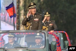 FILE - Cambodian Prime Minister Hun Sen salutes, along with his son, Lt. Gen. Hun Manet, during an inspection of troops at a ceremony in Phnom Penh, Cambodia, Jan. 24, 2019.
