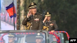 FILE - Cambodian Prime Minister Hun Sen salutes, along with his son Lt. Gen. Hun Manet during an inspection of troops at a ceremony in Phnom Penh, Cambodia, Jan. 24, 2019.