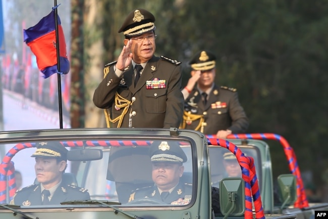 FILE - Cambodian Prime Minister Hun Sen salutes, along with his son, Lt. Gen. Hun Manet, during an inspection of troops at a ceremony in Phnom Penh, Cambodia, Jan. 24, 2019.