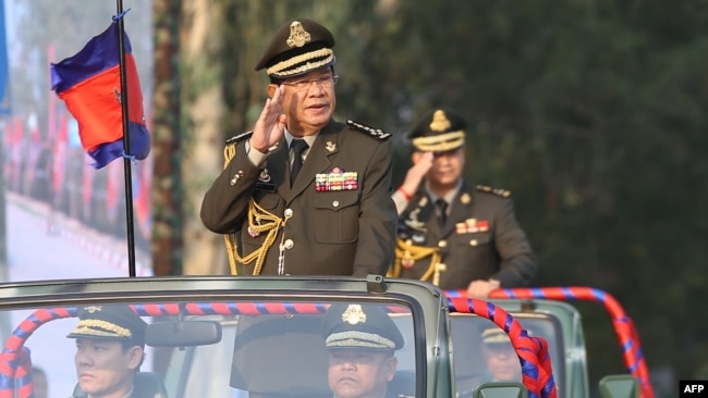 FILE - Cambodian Prime Minister Hun Sen salutes, along with his son Lt. Gen. Hun Manet during an inspection of troops at a ceremony in Phnom Penh, Cambodia, Jan. 24, 2019.