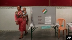 A woman carrying her daughter leaves after casting vote in a polling station during the fifth round of multi-phase national elections in Mumbai, India, May 20, 2024.