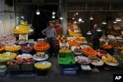 Fruit sellers talk as they wait for customers in Tehran, Iran, ahead of the Persian New Year, known as Nowruz, March 15, 2023. Iran's bazaars are packed ahead of the holiday, but there's little cheer as customers survey the soaring prices.