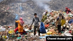 Waste picker Rajdin, 17, looks for recyclable material during a heat wave at a garbage dump on outskirts of Jammu, India, Wednesday, June 19, 2024. (AP Photo/Channi Anand)
