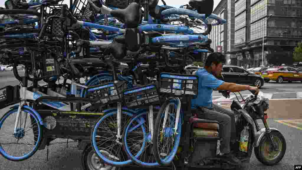 A man rides a tricycle loaded with bicycles on a street in Beijing.