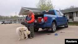 Wildfire evacuee Colin Guilder and his dog, Sheba, are pictured at a gas station and motel in northern Alberta the day after a wildfire caused the evacuation of communities on the southern edge of Fort McMurray, May 15, 2024.