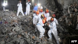 资料照片: 2022年5月5日救援人员从长沙市一栋倒塌的六层建筑中抬出一名幸存者