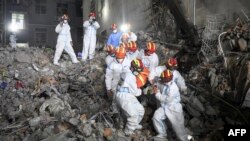 FILE - This photo taken early on May 5, 2022 shows rescuers carrying a survivor out of a collapsed six-story building in Changsha, central China's Hunan province. (Photo by CNS / AFP)