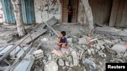 (FILE) A Palestinian boy sits at the site of an Israeli strike on a house, amid the Israel-Hamas conflict, in Maghazi refugee camp in the central Gaza Strip, August 14, 2024.