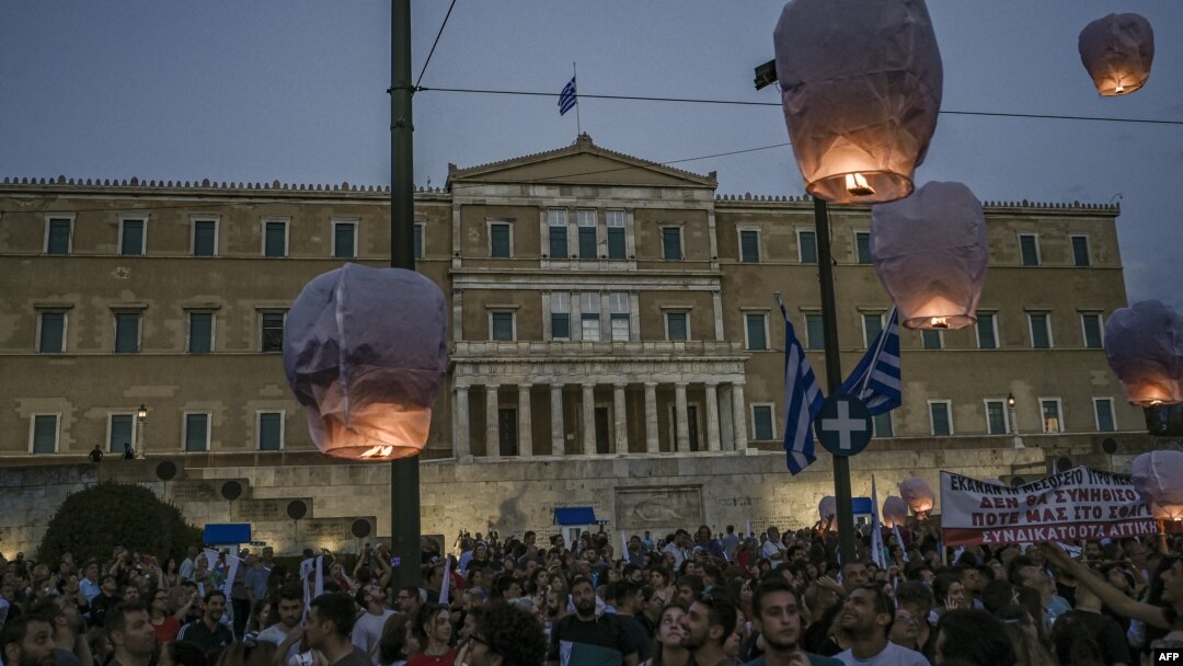 Para pengunjuk rasa melepaskan balon udara di depan parlemen Yunani di tengah Athena, 15 Juni 2023, sebagai penghormatan kepada para korban menyusul kecelakaan kapal yang menewaskan sedikitnya 78 migran dari semenanjung Peloponeese, Yunani. (SPYROS BAKALIS/AFP)