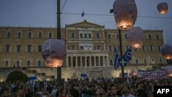 Para pengunjuk rasa melepaskan balon udara di depan parlemen Yunani di tengah Athena, 15 Juni 2023, sebagai penghormatan kepada para korban menyusul kecelakaan kapal yang menewaskan sedikitnya 78 migran dari semenanjung Peloponeese, Yunani. (SPYROS BAKALIS/AFP)