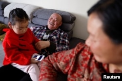 Wu Yonghou, 58, rests with his granddaughter, next to his wife Yang Chengrong, 60, after a meal on Chinese Lunar New Year's Eve, at their apartment in a town bordering Beijing, in Hebei province, China February 9, 2024. (REUTERS/Tingshu Wang)