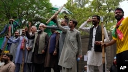 Supporters of former Prime Minister Imran Khan gather with sticks and chant slogans outside Khan's residence, in Lahore, Pakistan, March 17, 2023.