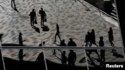 FILE - Workers are reflected in an office building's windows in Sydney's Barangaroo business district in Australia's largest city, May 8, 2017. Millions of Australians can now break free from the stress of after-hours calls and emails from work.