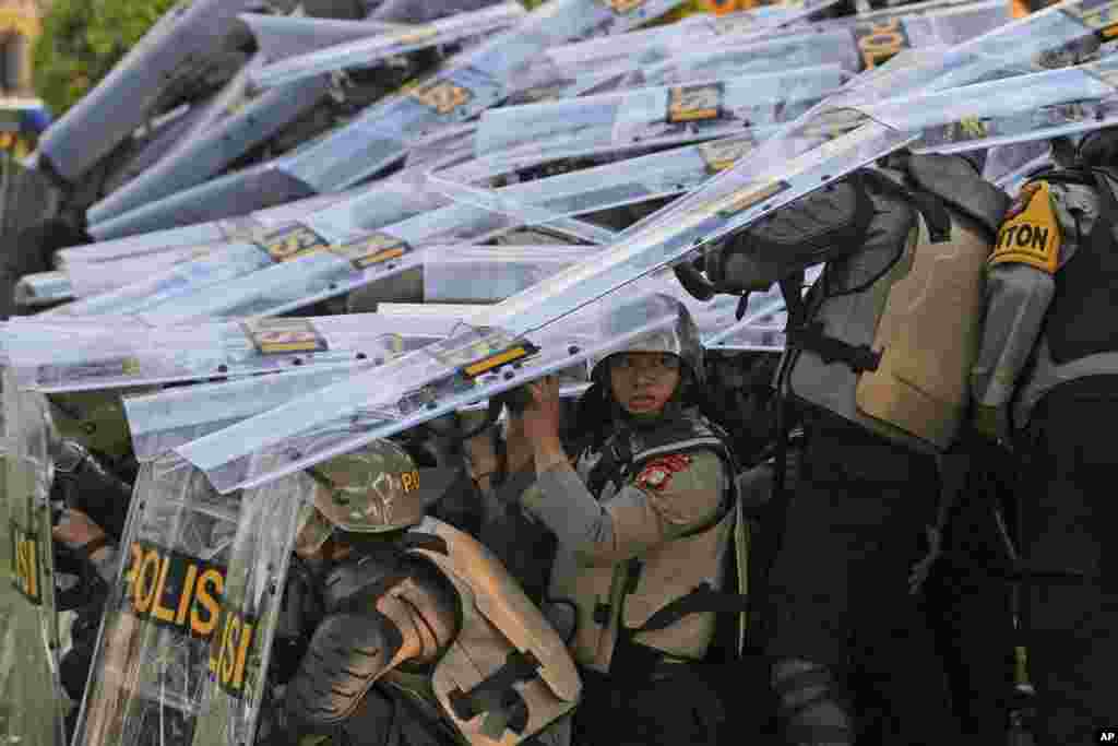 Riot police officers take defensive positions as they clash with protesters during a rally against controversial changes to election laws that could further enhance the political influence of outgoing President Joko Widodo, at the parliament building in Jakarta, Indonesia.