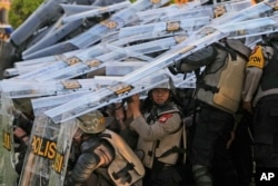 Petugas polisi antihuru-hara saat bentrok dengan pengunjuk rasa terkait perubahan kontroversial undang-undang pemilu di Gedung DPR di Jakarta, 22 Agustus 2024. (Foto: AP)