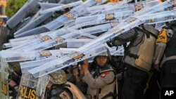 Riot police officers take defensive positions as they clash with protesters during a rally against controversial changes to election laws that could further enhance the political influence of outgoing President Joko Widodo, at the parliament building in Jakarta, Indonesia.