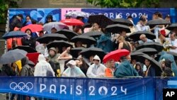 Spektatorët duke u mbrojtur nga shiu në Paris (26 korrik 2024)