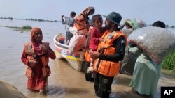 In this photo released by Rescue 1122 Emergency Department, rescue workers evacuate villagers through a boat from a flooded area of Bahawalnagar district in Pakistan's Punjab province, Aug. 23, 2023.