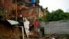 Los residentes se paran en un patio trasero que se derrumbó el día después de que un arroyo se desbordara debido a las fuertes lluvias en Limón, en las afueras de Caracas, Venezuela, el viernes 11 de noviembre de 2022.