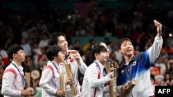 Bronze medalists S. Korea's Lim Jonghoon takes a selfie with: gold medalists China's Wang Chuqin and China's Sun Yingsha, silver medalists N. Korea's Ri Jong Sik, and N. Korea's Kim Kum Yong and bronze medalist Shin Yubin, July 30, 2024. 