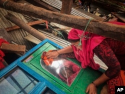 FILE - A woman salvages belongings from her home damaged by Cyclone Mocha in Cox's Bazar, Bangladesh, May 15, 2023. (AP Photo)