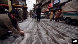 A man scoops up hailstones after they rained down in Peshawar, Pakistan, March 30, 2024. Heavy rains killed eight people, mostly children, and injured 12 in Pakistan's northwest, an official said Saturday. 