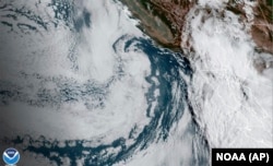 This Aug. 19, 2023 11:38 a.m. EDT satellite image provided by the National Oceanic and Atmospheric Administration shows Hurricane Hilary, right, off Mexico’s Pacific coast.