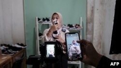 A staff of a small shoe manufacturer shows their new products to make an introductory video to be posted on social media in Bogor, West Java, Sept. 27, 2023. They have been selling their handmade sports and casual shoes through social media for almost two years. 