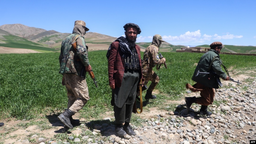 FILE - Armed Taliban security personnel walk along a wheat field in Argo district, Badakhshan province, on May 6, 2024. 
