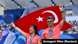 Peraih medali perak campuran cabang menembak Sevval Ilayda Tarhan dari Turki dan Yusuf Dikec dari Turki berpose dengan medali mereka dan bendera Turki selama perayaan peraih medali di Champions Park (Foto: REUTERS/Annegret Hilse)