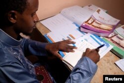 Mamadou Safaiou Barry, a 25-year-old from Guinea, practices writing words in Arabic in a sideways orientation in east Cairo, Egypt, September 23, 2023. (REUTERS/Fatma Fahmy)