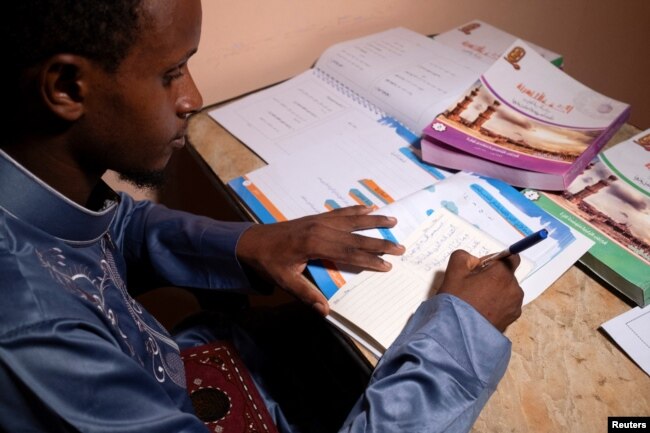 Mamadou Safaiou Barry, a 25-year-old from Guinea, practices writing words in Arabic in a sideways orientation in east Cairo, Egypt, September 23, 2023. (REUTERS/Fatma Fahmy)