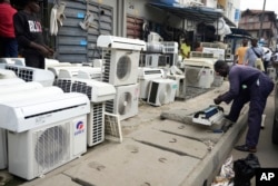 A man repairs air conditioners on the street in Lagos, Nigeria, Monday, July 15, 2024. (AP Photo/Sunday Alamba)