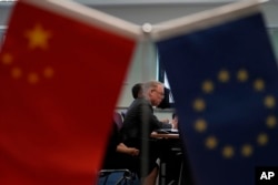 Jens Eskelund, president of the European Chamber is framed by the Chinese and European Union flags during the launch of the European Business in China: Business Confidence Survey in Beijing, Wednesday, June 21, 2023. Foreign companies are shifting investments and their Asian headquarters out of China as confidence plunges following the expansion of an anti-spying law and other challenges, the business group said Wednesday. (AP Photo/Ng Han Guan)