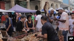 Shoppers gather around a cart of garlic at a street market in Havana, Cuba, March 16, 2024. 