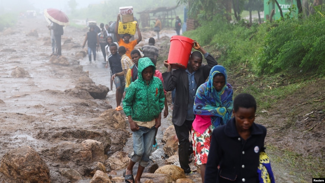Locals in the Chiradzulu district walk with salvaged possessions to safer ground after mud slid and rocks fell in the wake of Cyclone Freddy in Blantyre, Malawi, March 15, 2023.