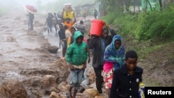 Locals in the Chiradzulu district walk with salvaged possessions to safer ground after mud slid and rocks fell in the wake of Cyclone Freddy in Blantyre, Malawi, March 15, 2023.