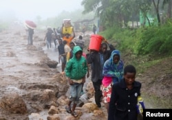Locals in the Chiradzulu district walk with salvaged possessions to safer ground after mud slid and rocks fell in the wake of Cyclone Freddy in Blantyre, Malawi, March 15, 2023.