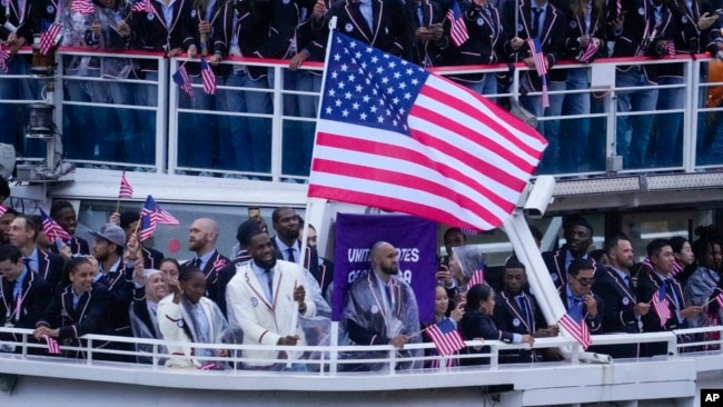 Kapal yang membawa tim Olimpiade Amerika Serikat dengan pebasket Lebron James sebagai pembawa bendera, menyusuri Sungai River di Paris, Prancis, dalam upacara pembukaan Olimpiade Musim Panas, Jumat, 26 Juli 2024. (Foto: Lindsey Wasson/AP Photo)