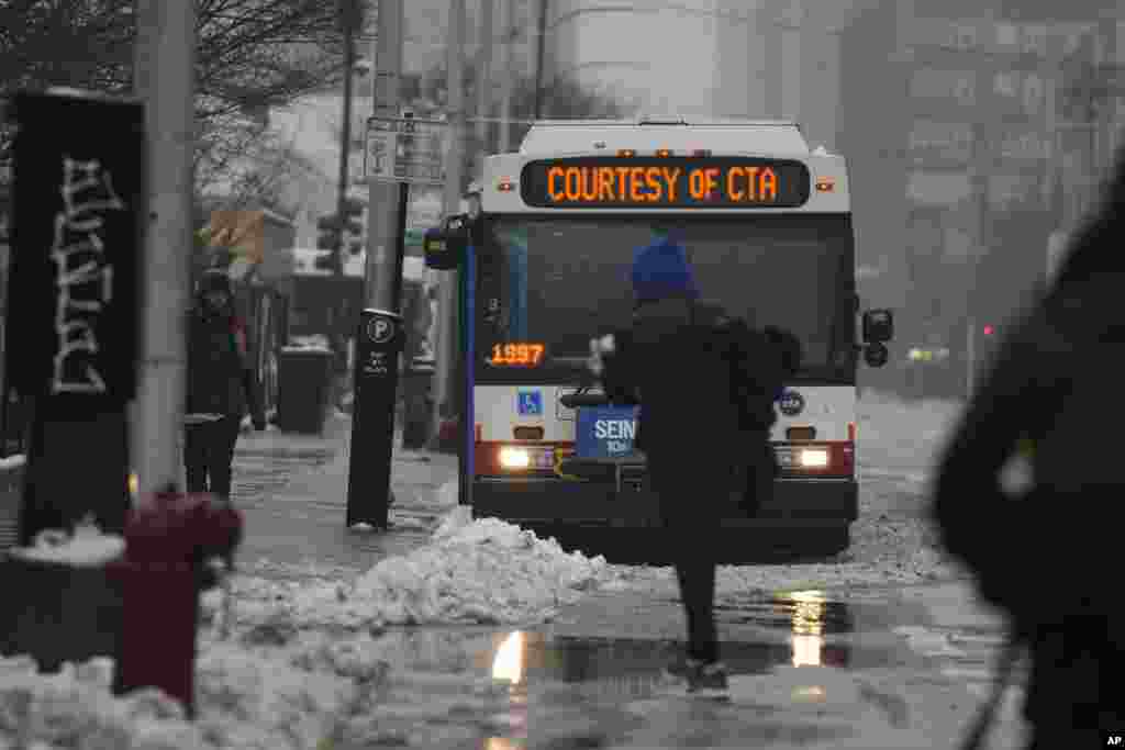 Los migrantes regresan a los autobuses de &quot;calentamiento&quot; proporcionados por la Autoridad de Tránsito de Chicago después de recibir donaciones de ropa y alimentos de los voluntarios de la Iglesia Comunitaria Starting Point.