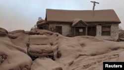 Sebuah rumah dan mobil tertutup debu vulkanik setelah erupsi gunung berapi Shiveluch di wilayah Kamchatka di Timur Jauh Rusia, 11 April 2023. (Institut Vulkanologi dan Seismologi/Handout via Reuters)