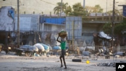 ARCHIVO: Una mujer cruza una calle después de choques entre la policía y hombres armados en el vecindario de Portail, en Puerto Príncipe, Haití, el 29 de febrero de 2024.