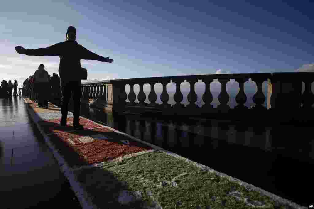A person prays while walking on a rug made of colored salt toward the Christ the Redeemer statue after a Catholic Mass celebrating Corpus Christi in Rio de Janeiro, Brazil.