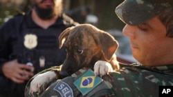 FILE - A Brazilian soldier carries a dog after rescuing it from a flooded area after heavy rain in Canoas, Rio Grande do Sul state, Brazil, May 9, 2024.