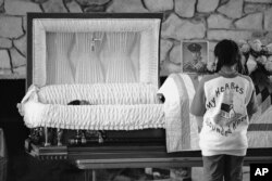 FILE - A girl stands in front of the casket of Lawrence Lamont during his funeral in Wounded Knee, South Dakota, May 4, 1973.