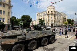 People walk past an armoured personnel carrier in the city of Rostov-on-Don, on June 24, 2023.