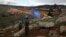 FILE - UN peacekeepers hold their flag as they observe Israeli excavators' attempt to destroy tunnels built by Hezbollah, near the southern Lebanese-Israeli border village of Mays al-Jabal, Lebanon on Dec. 13, 2019. 