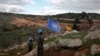 FILE - U.N. peacekeepers hold their flag as they observe Israeli excavators' attempt to destroy tunnels built by Hezbollah, near the southern Lebanese-Israeli border village of Mays al-Jabal, Lebanon, Dec. 13, 2019. 