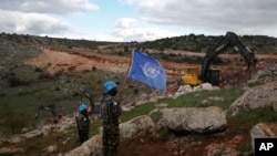 Para tentara pasukan perdamaian PBB mengibarkan bendera PBB sambil mengamati alat berat Israel menghancurkan terowongan dekat perbatasan selatan Lebanon-Israel di desa Mays al-Jabal, Lebanon, 13 Desember 2019. (Foto: Hussein Malla/AP Photo)